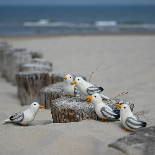 Dekorative Möwenfiguren aus Filz auf einem sandigen Strand