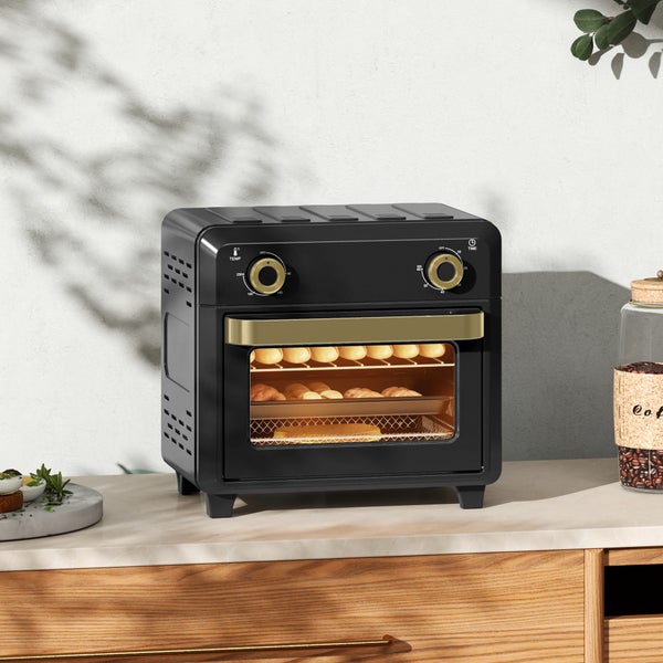 Kompakter schwarzer Mini-Backofen mit goldfarbenen Akzenten, zwei Drehreglern und Glastür, auf einer Arbeitsplatte mit Backwaren im Inneren.