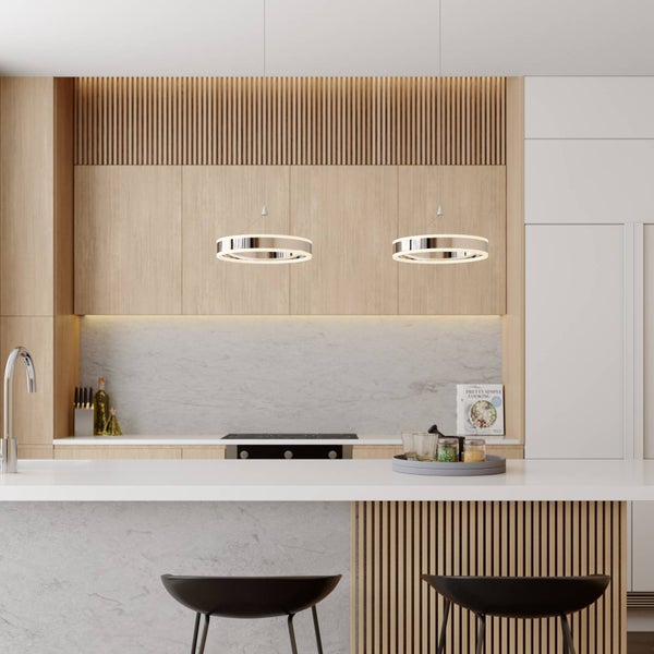 Zwei moderne ringförmige LED-Pendelleuchten in Chrom hängen in einer hellen Küche über einer Kücheninsel mit Holzlamellen.