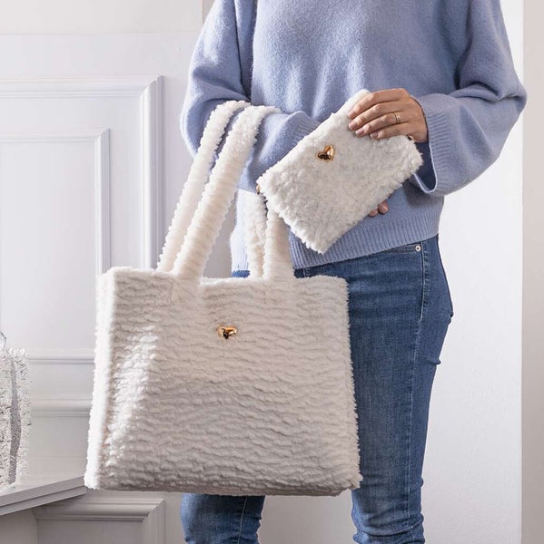 Person hält eine flauschige Handtasche und eine Geldbörse mit Herzdetail