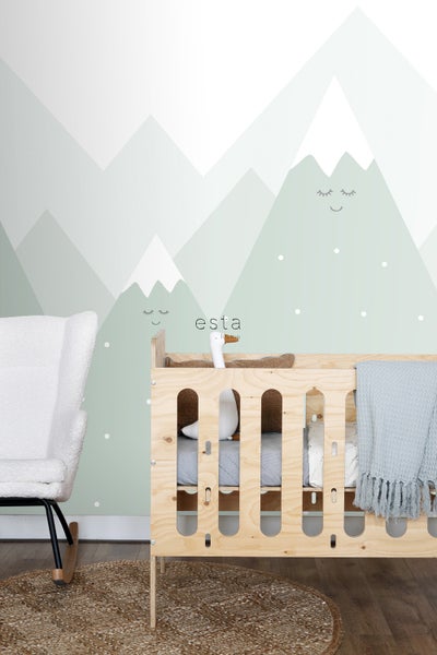 Babyzimmer mit Holzkinderbett, Schaukelstuhl und Bergtapete