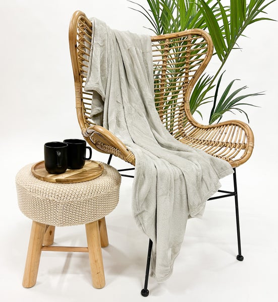 Szene mit Rattansessel, weicher Decke, Hocker, Tablett, Tassen und Pflanze.