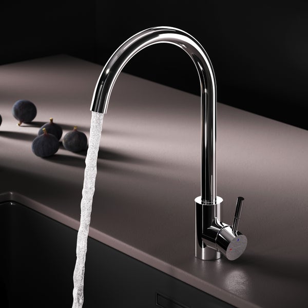 Verchromter Wasserhahn mit Wasserstrahl und einigen Feigen auf der Arbeitsfläche