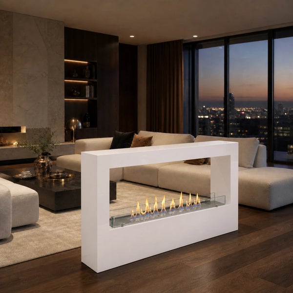 Moderner freistehender Ethanol Kamin in Weiß als Raumteiler in einem eleganten Wohnzimmer mit Stadtblick bei Abenddämmerung.