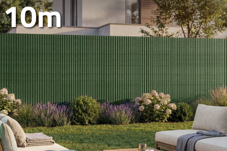 Sichtschutzmatte in Rollenform mit zehn Meter Laenge zur Befestigung an Gartenzaeunen im Vorgarten mit Blumenbeeten und Sitzgelegenheit.
