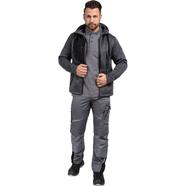 Mann in grauer Strickfleecejacke mit Kapuze, grauer Arbeitshose mit Kniepolstertaschen und schwarzen Arbeitsschuhen.