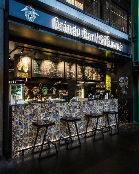 Ansicht einer Bar mit Fliesenmuster, Barhockern und beleuchtetem Tresen