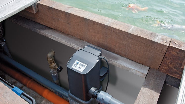 Elektronische Steuerung für Teichpumpen an einem Koiteich mit Holzumrandung und Rohrleitungen.