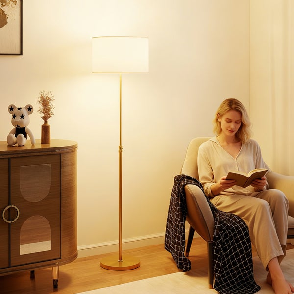 Wohnzimmer-Szene mit Stehlampe, Kommode und lesender Frau im Sessel