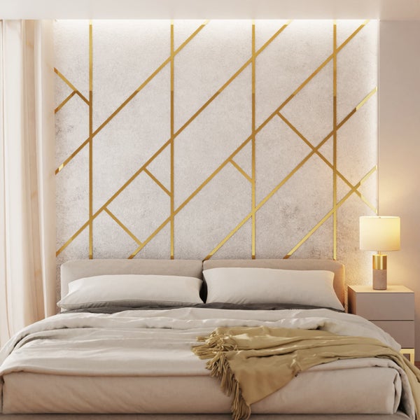 Schlafzimmer mit Bett und Nachttischlampe vor einer Wand mit goldenem geometrischen Muster.