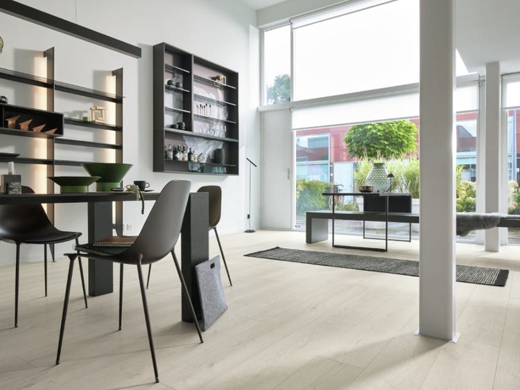 Modernes, lichtdurchflutetes Esszimmer mit hellem Holzboden, schwarzem Esstisch, Stühlen und wandmontierten Regalsystemen.
