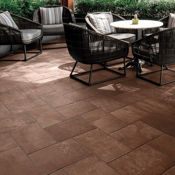 Terrassengestaltung mit großformatigen Steinplatten im Verband auf einer Außenterrasse mit Sitzgruppe aus Rattanmöbeln.