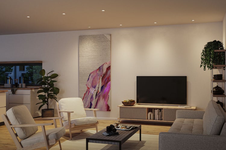 Hell gestaltetes Wohnzimmer mit Deckeneinbaustrahlern, zwei Sesseln, einem Sofa und einem TV-Lowboard aus Holz in modernem Stil.