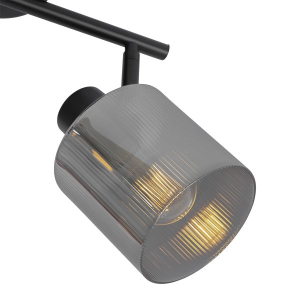 Strahler mit einem Schirm aus geriffeltem Rauchglas und schwarzem Metallgestell.