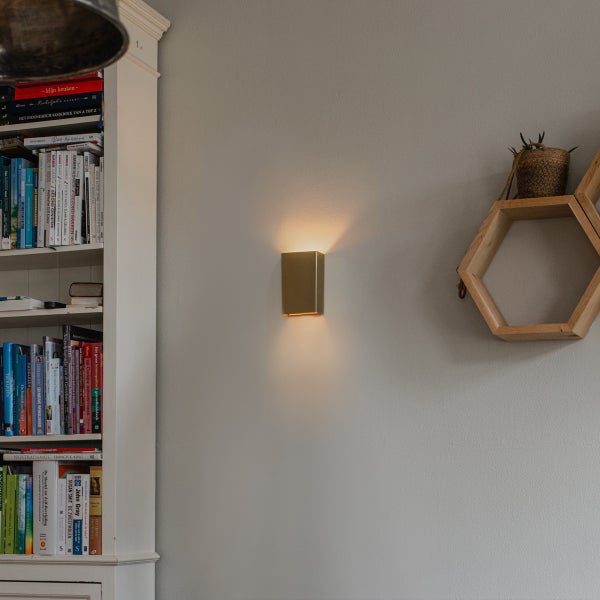 Wandleuchte neben einem Bücherregal und einem sechseckigen Regal