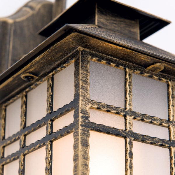 Detailansicht einer Außenwandleuchte im Laternenstil mit antikem Metallgestell, dekorativem Gitter und mattiertem Glas.
