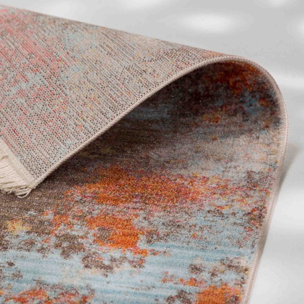 Bunt gemusterter Webteppich mit abstrakten Motiven, Fransen und sichtbarer Unterseite.