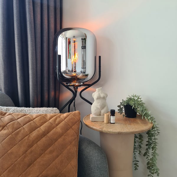 Dekorative Szene mit Lampe, Statue und Pflanze auf einem Beistelltisch.