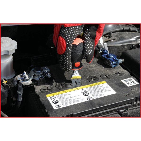 Nahaufnahme einer Hand mit Handschuh, die eine Autobatterie mit einem Schraubenschlüssel bearbeitet