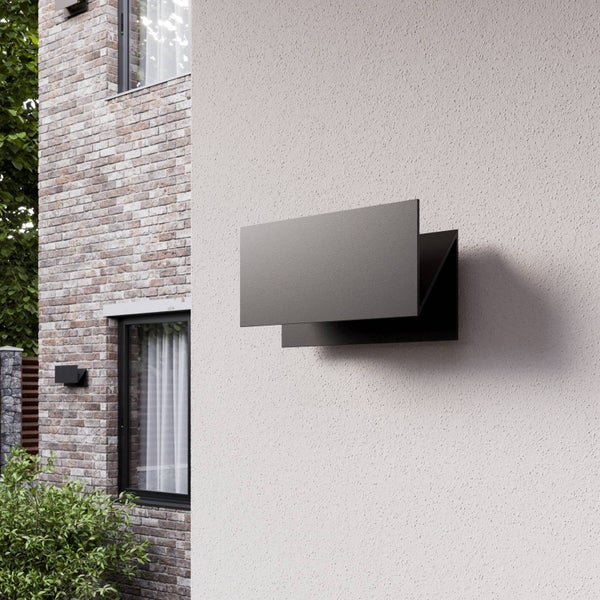 Moderne rechteckige Außenwandleuchte in Anthrazit an einer hellen verputzten Wand neben einer Klinkerfassade mit Fenster.