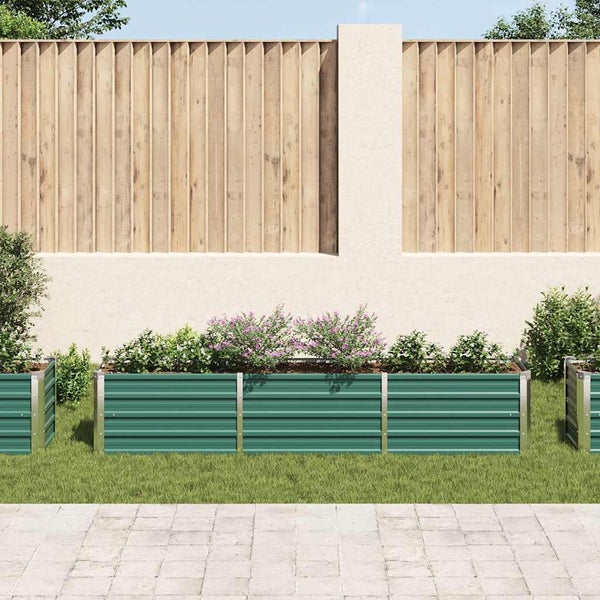 Rechteckiges Hochbeet aus Metall mit gerippter Struktur in einem Garten vor einem Holzzaun und einer verputzten Wand.