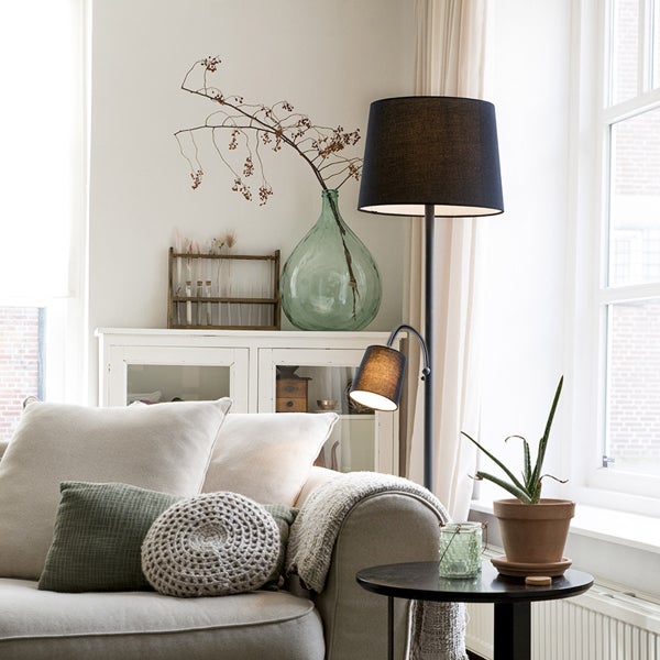 Wohnzimmer mit Stehlampe, Sofa, Tisch und Dekoration