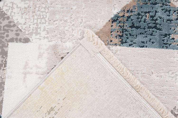 Teppich mit abstraktem Muster in Beige, Grau und Blau, inklusive Fransen und sichtbarer Rückseite.