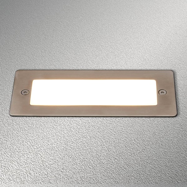 Rechteckige LED-Einbauleuchte mit Edelstahlrahmen auf einer strukturierten Wand.