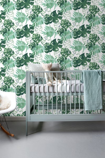 Kinderzimmer mit tropischer Blättertapete, Gitterbett und Schaukelstuhl