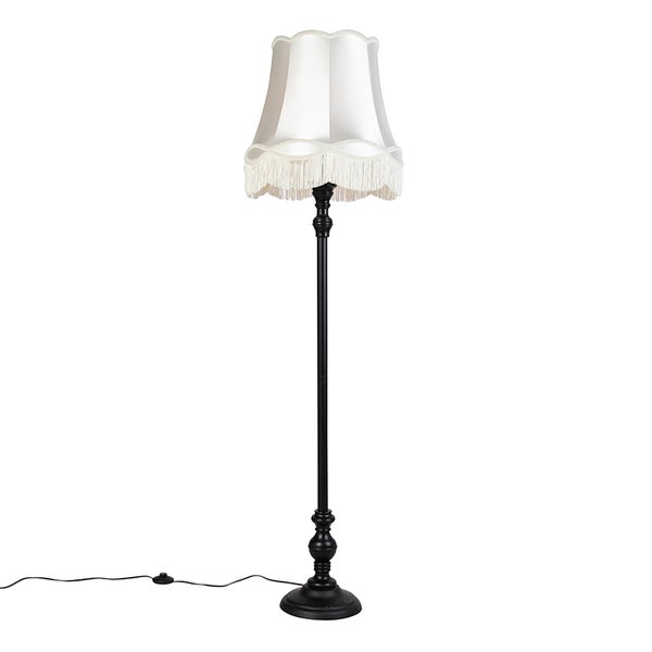 Klassische Stehlampe mit schwarzem Metallgestell und weißem Stoffschirm mit Fransen.
