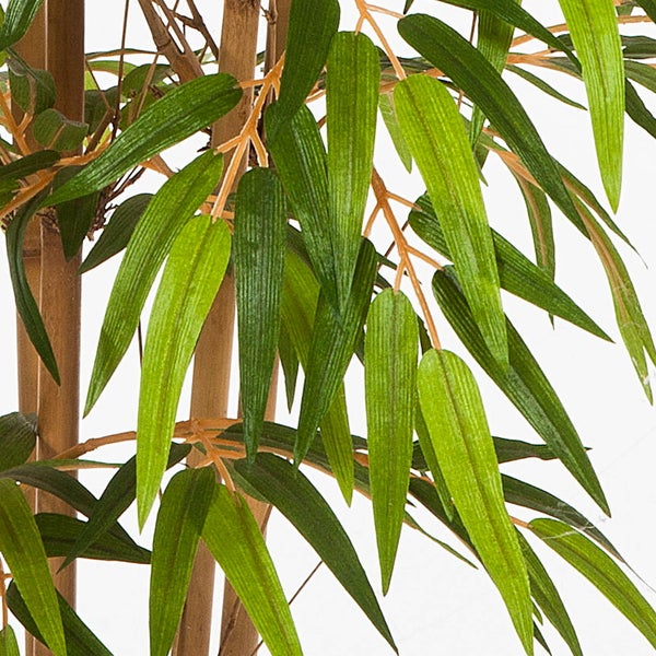 Nahaufnahme einer künstlichen Bambuspflanze mit grünen, länglichen Blättern und hellbraunen Halmen.