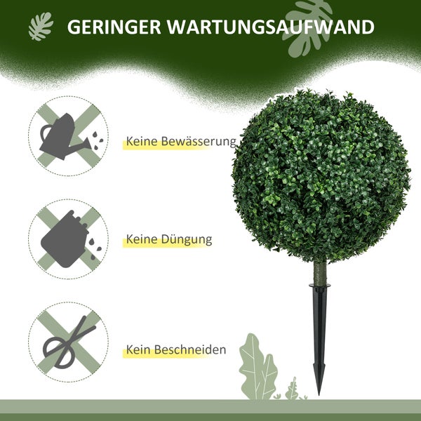 Vier künstliche Buchsbaumkugeln auf einer Rasenfläche vor einem hellen Wohnhaus mit Veranda und Treppenaufgang.