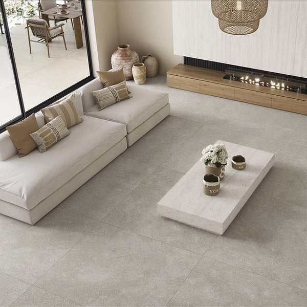 Geräumiges Wohnzimmer mit hellen Bodenfliesen in Steinoptik, großem Sofa, Kamin und Zugang zur Terrasse in modernem Design.