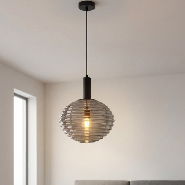 Pendelleuchte mit geriffeltem Schirm aus Rauchglas, schwarzer Aufhängung, eingeschaltet in einem hellen Raum hängend.