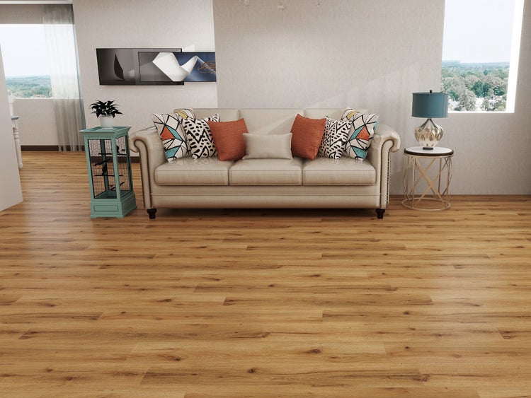Helles Wohnzimmer mit Bodenbelag in Eichenoptik, beige Couch mit Kissen, Beistelltisch mit Lampe und großen Fenstern.