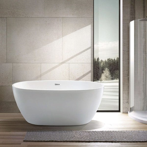 Freistehende Badewanne in modernem Badezimmer mit großen Fliesen an der Wand und bodentiefem Fenster mit Blick in den Wald