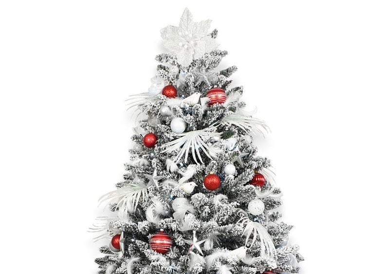 Weihnachtsbaum mit Kunstschnee dekoriert mit Weihnachtskugeln in Rot und Weiss sowie Sternen und Vögeln als Baumschmuck.