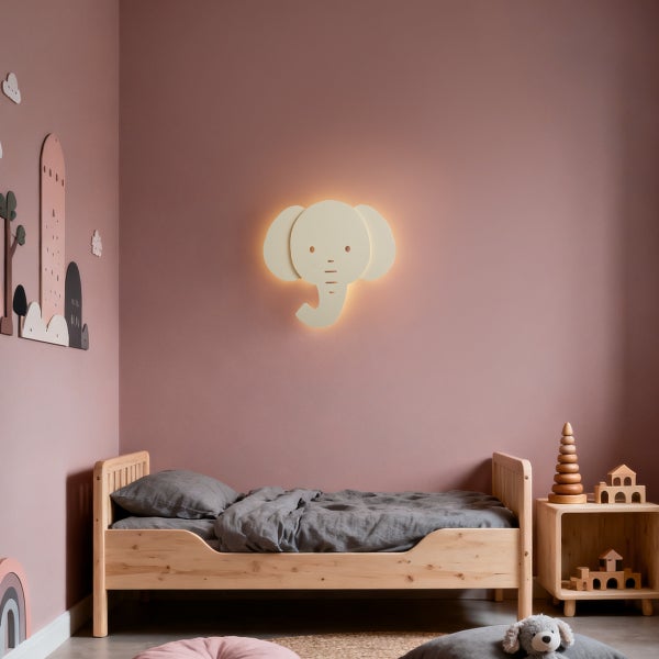 Hell eingerichtetes Kinderzimmer mit Holzbett und einer leuchtenden Wandlampe in Form eines Elefanten.
