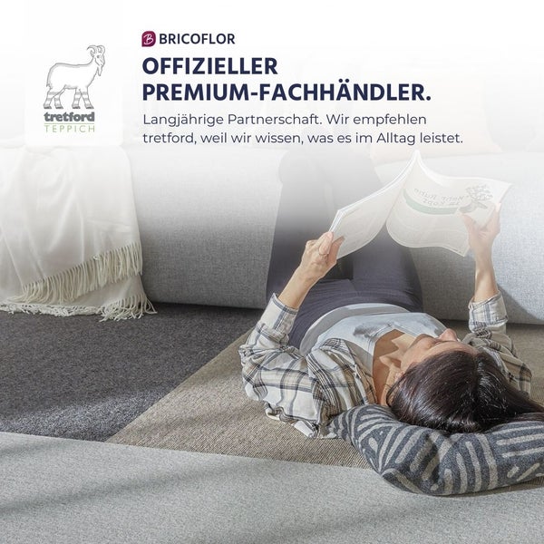Eine Person liegt auf einem tretford Teppich und liest. Mit tretford TEPPICH Logo und BRICOFLOR Logo als offizieller Premium-Fachhändler.