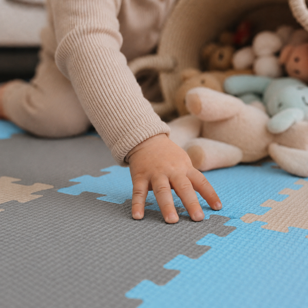 Kind spielt auf einer Puzzlematte aus Schaumstoff mit ineinandergreifenden Puzzleteilen im Kinderzimmer.
