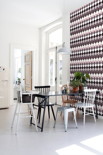 Esszimmer mit Rautentapete, Esstisch und verschiedenen Stühlen.