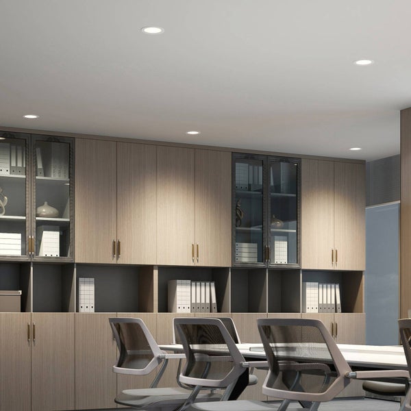 Moderner Büroraum mit LED-Einbaustrahlern in der Decke, die einen großen Wandschrank aus Holz beleuchten.