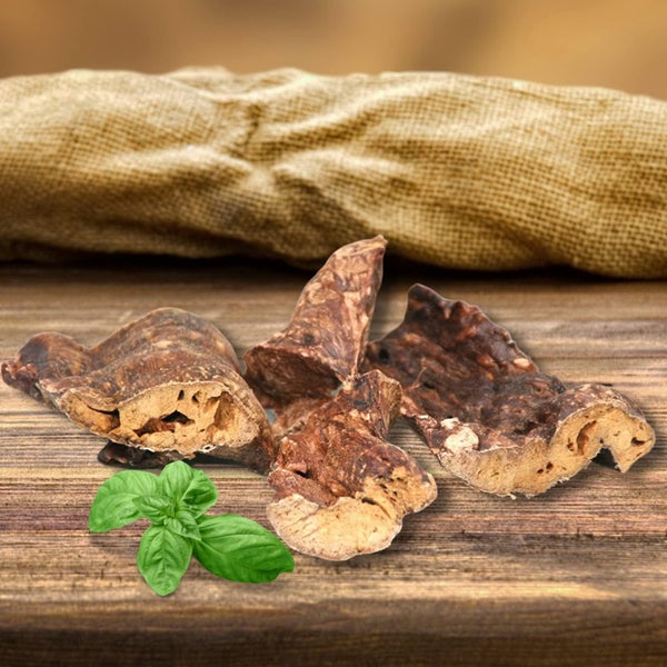 Hundekauartikel aus Rinderkopfhaut mit Basilikum auf Holzbrett