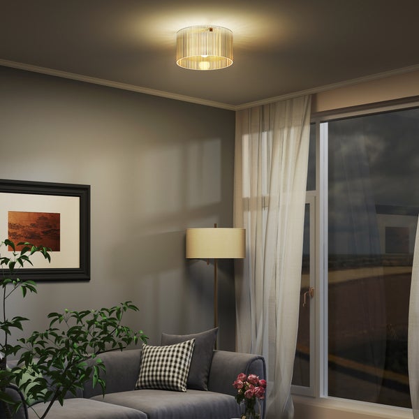 Moderne Deckenleuchte mit goldenen Lamellen in einem gemütlichen Wohnzimmer mit grauem Sofa, Stehlampe und Vorhängen.