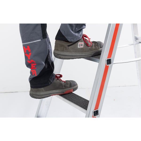 Person mit Arbeitsschuhen auf einer Leiter