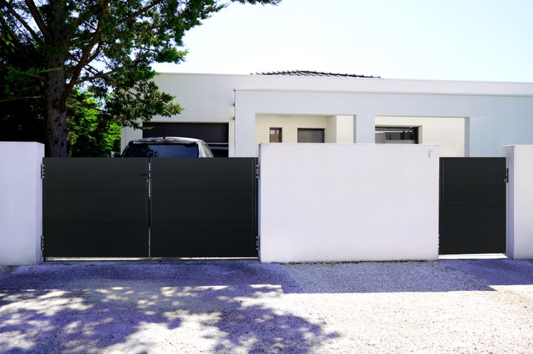 Modernes Haus mit schwarzem Schiebetor und weißer Mauer