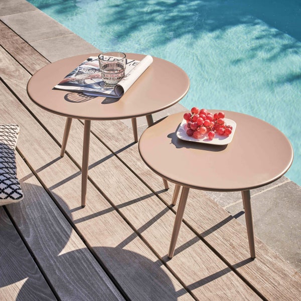 Zwei runde Metall-Beistelltische in verschiedenen Höhen auf einer Holzterrasse am Pool mit Magazin, Wasserglas und einer Schale Weintrauben.