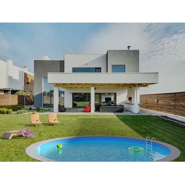 Ein modernes Haus mit Pool und Gartenmöbeln auf einem Rasen