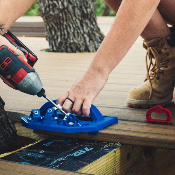Blaue Bohrschablone für den Terrassenbau aus Kunststoff mit drei Metallbohrbuchsen und Griff.