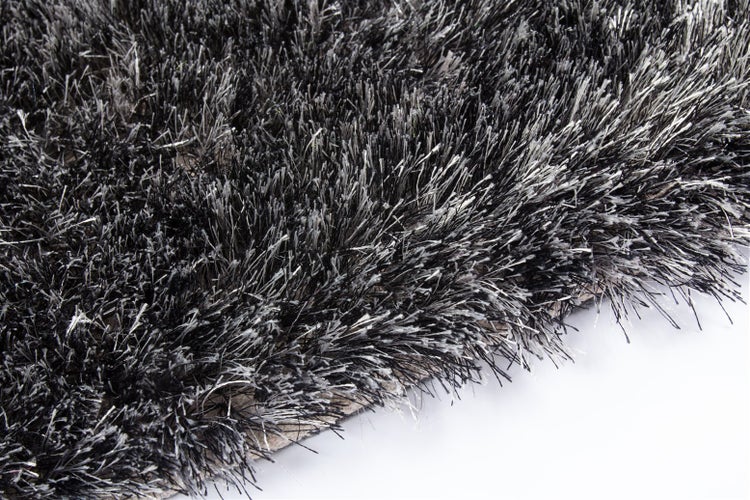 Detailaufnahme eines Hochflor-Teppichs in Schwarz und Grau mit langen, dichten Fasern.